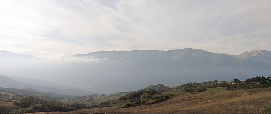 La vallata avvolta nella foschia, con i profili dei monti sullo sfondo